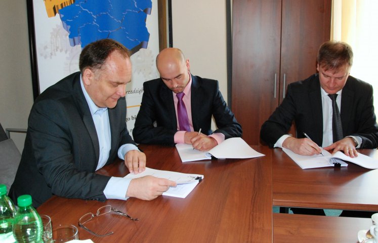 Marcin Pawełek (w środku) podpisuje umowę umożliwiającą udzielanie lokalnym przedsiębiorcom kolejnych poręczeń kredytowych.  FOT: http://www.umwd.dolnyslask.pl