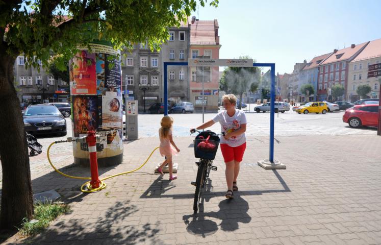 Mama z dzieckiem przechodzi przez kurtynę wodna na ul. Wrocławskiej