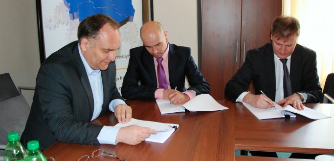 Marcin Pawełek (w środku) podpisuje umowę umożliwiającą udzielanie lokalnym przedsiębiorcom kolejnych poręczeń kredytowych.  FOT: http://www.umwd.dolnyslask.pl